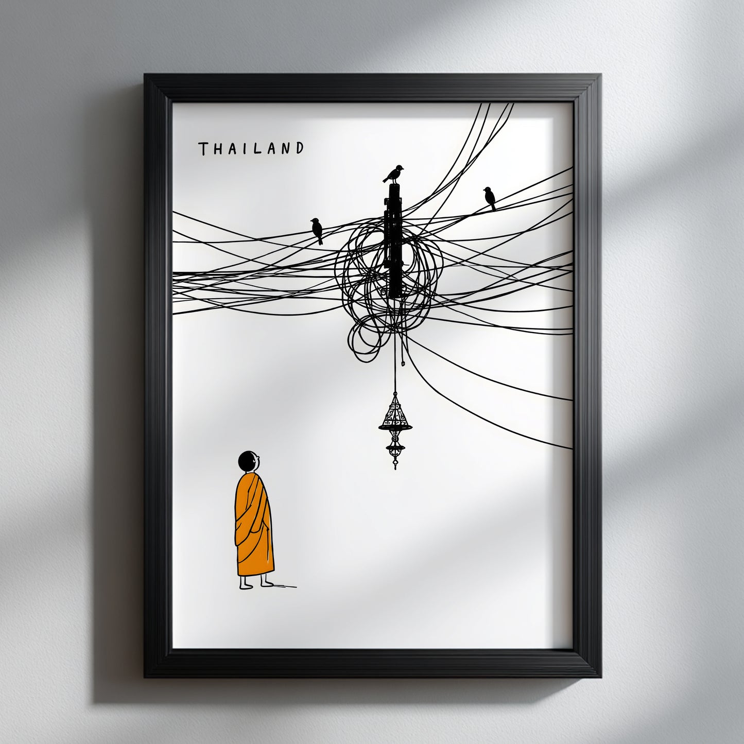 Black framed Thailand cable mess poster on a pale wall, showing a Buddhist monk in an orange robe beneath chaotic black overhead wires, small birds and a hanging Thai-style lamp. A clean, funny Thailand travel print with strong white space and modern cultural wall art style.
