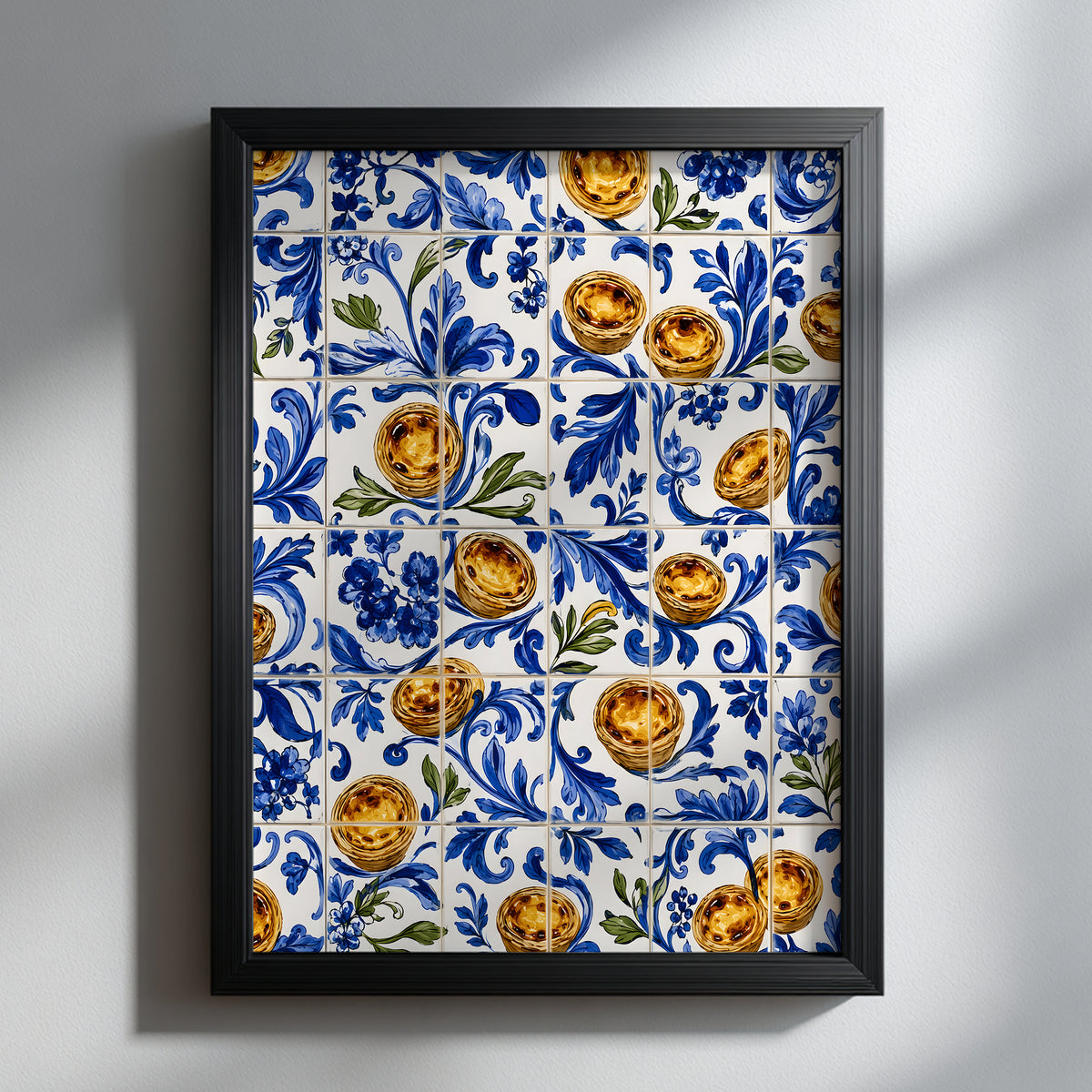 Black framed Portuguese azulejo wall art featuring golden pastel de nata custard tarts among blue floral tile patterns, displayed against a light neutral wall.