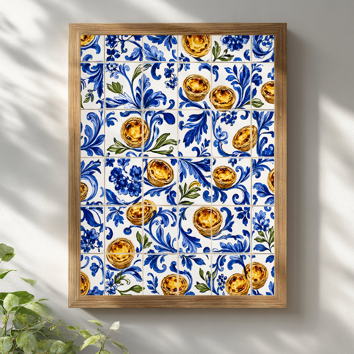 Wooden framed pastel de nata Portuguese azulejo wall art displayed on a clean white wall, featuring blue floral tilework, golden custard tarts and green leaf details.