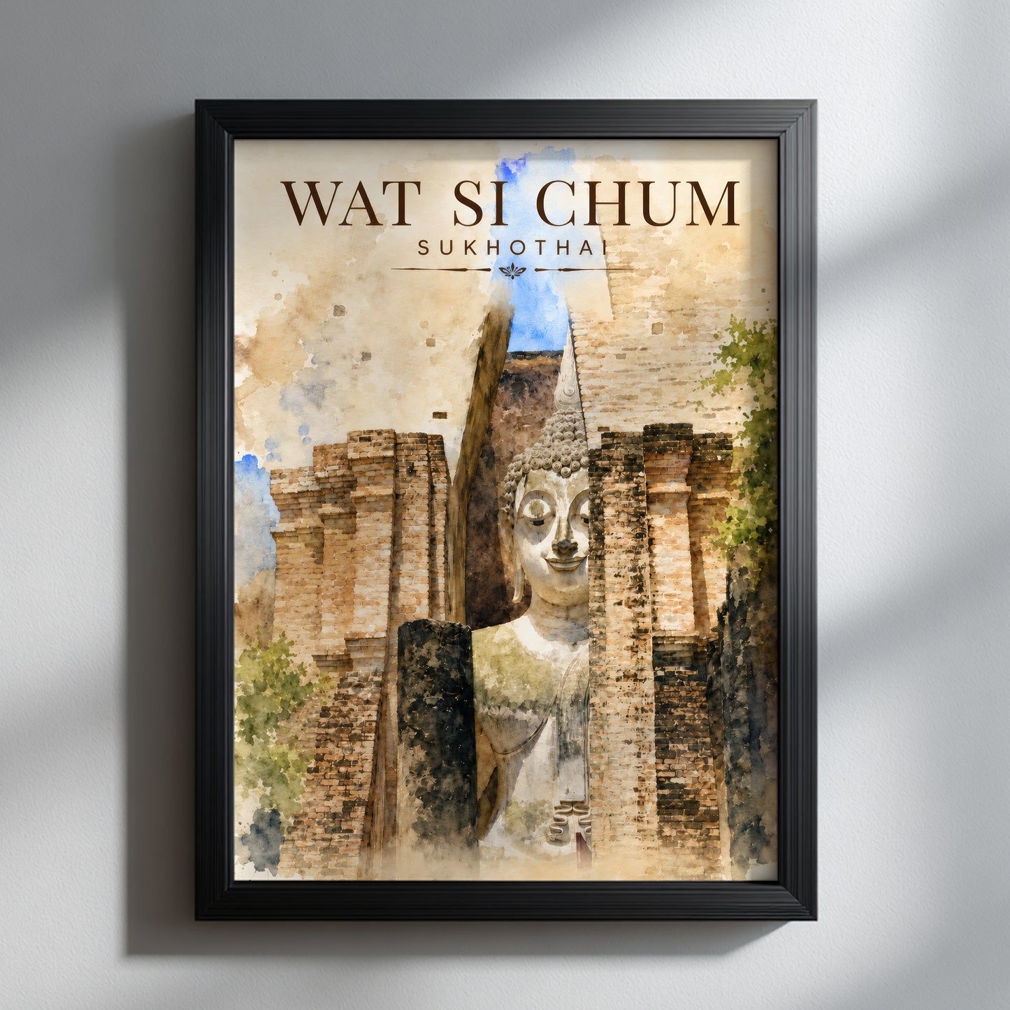 Wat Si Chum Buddha art print in a black frame on a light wall, showing Sukhothai temple ruins in warm brown and cream watercolour tones with soft blue and green details.