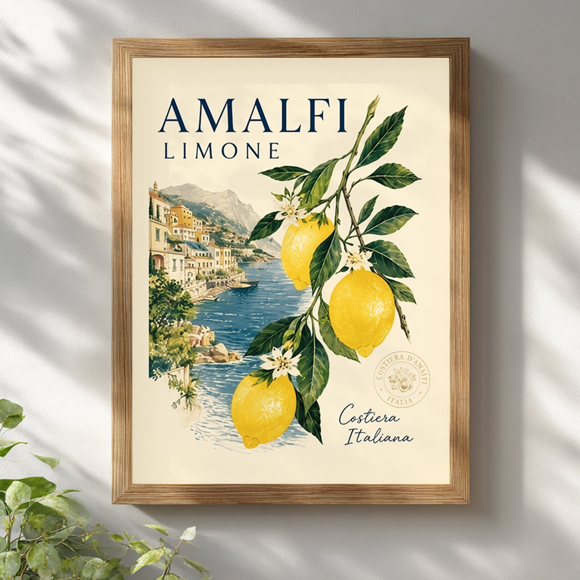 Wooden framed Amalfi Coast lemon print on a white wall with soft natural shadow. The poster shows bright yellow lemons, green leaves and an Italian seaside village by blue water, giving a fresh Mediterranean summer feel for kitchen, dining room or travel inspired decor.