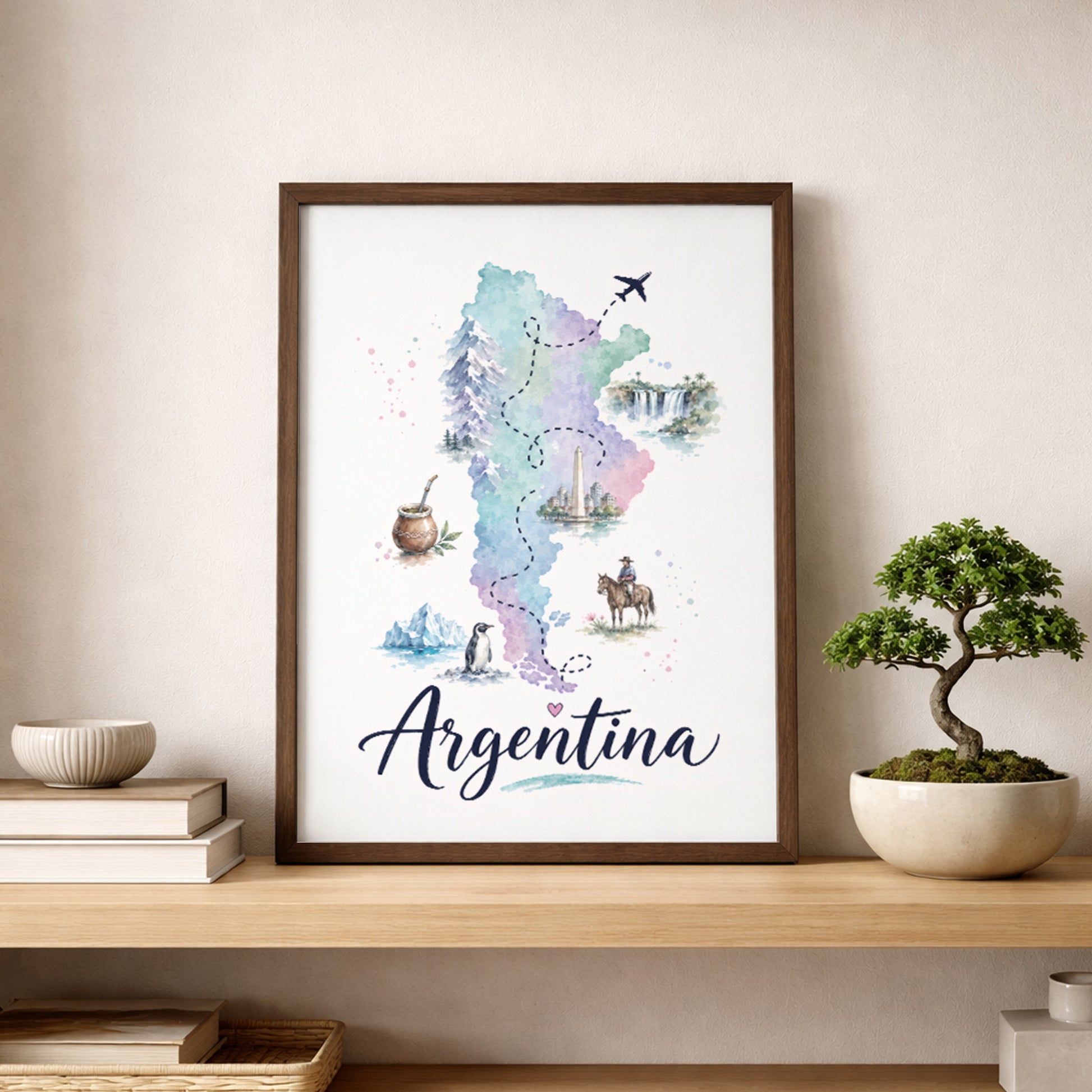 Framed Argentina map wall art resting on a wooden shelf in a calm neutral room. The pastel watercolour map is decorated with small cultural, wildlife and travel illustrations, with large cursive Argentina lettering beneath. A cream sofa, stacked books, ceramic decor and a small bonsai-style plant complete the warm travel-inspired display.