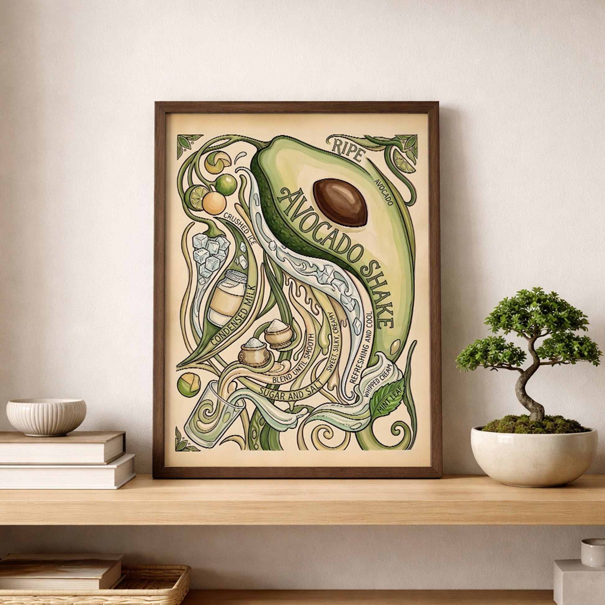 Avocado shake poster displayed on a wooden shelf beside a small bonsai plant and simple decor. The framed print features a sliced avocado, curling vines and hand-drawn recipe details in green and cream shades. The styling shows how the food poster works as kitchen wall art, shelf decor or botanical wall art in a clean and modern home space.