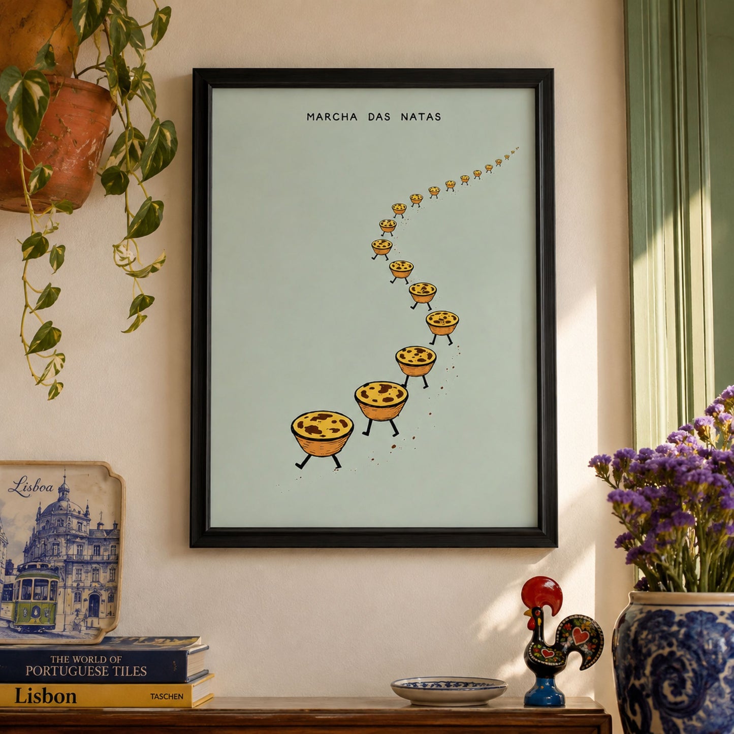 Pastel de nata wall art in a black frame displayed in a colourful lived-in interior with plants, flowers and decorative objects around the Portuguese food print.