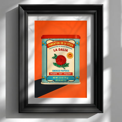 Framed Spanish kitchen wall art showing the Spanish Smoked Paprika Tin design on a bright orange background, styled in a black frame against a soft white wall. The artwork features a red tin lid, blue striped border, cream label and red flower, giving it a retro food art look. A strong image for Mediterranean kitchen decor, colourful dining room art and vintage packaging wall decor.