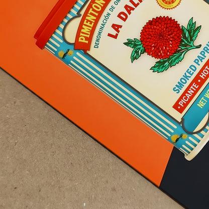Detailed close-up of the framed Spanish Smoked Paprika Tin artwork showing print depth, frame edge and paper surface in a real-life setting. The image focuses on the corner area of the orange design and vintage tin layout, helping show finish and presentation. Useful for Spanish food packaging art, retro kitchen print detail, framed wall decor and bold graphic artwork with a clean professional look.