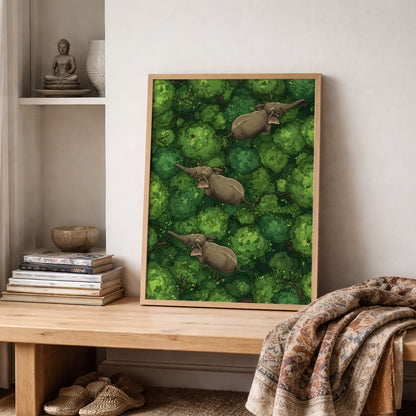 Framed elephant wall decor displayed on a wooden shelf beside folded textiles in a soft neutral room. The artwork features three elephants walking through layered green jungle treetops viewed from above, with strong leafy detail and earthy animal tones. Accurate for jungle elephant art, wildlife poster, tropical forest wall art, elephant print and travel-inspired nature decor listings.