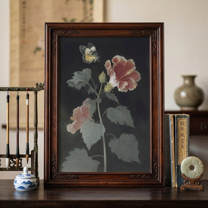 Malaysian hibiscus botanical wall art in a dark wood frame placed in a styled living room setting. The artwork shows Bunga Raya flowers and a Rajah Brooke’s Birdwing butterfly on a dark background. Vintage botanical wall art styled with classic décor, creating a calm and elegant focal point in the space.