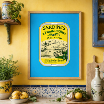 French sardine tin art print displayed in a wooden frame in a colourful kitchen, featuring a turquoise blue background and yellow vintage food packaging beside patterned tiles, ceramics and indoor plants.