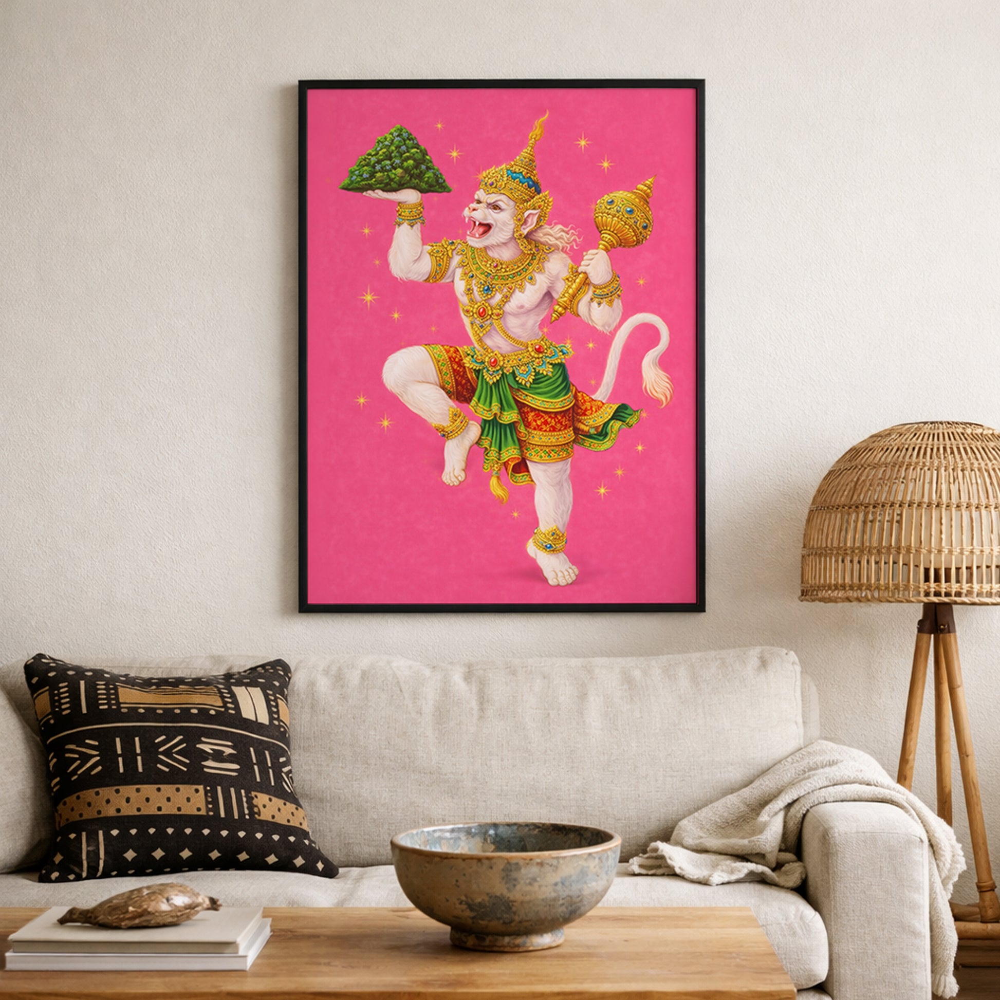 Thai Hanuman Ramakien art print displayed on a textured living room wall above neutral seating and woven decor elements. The vibrant pink mythology poster features the Hindu monkey god in traditional Thai costume with gold and green detailing. A bold spiritual wall decor statement inspired by Southeast Asian folklore and Hindu epic art.