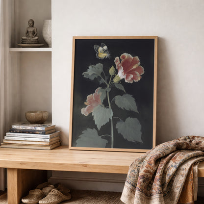 Malaysian hibiscus art print displayed on a shelf with books and textured fabric décor. The botanical artwork features the Bunga Raya flower and Rajah Brooke’s Birdwing butterfly on a dark background. Vintage botanical wall art styled in a calm, natural interior with soft tones and layered textures.