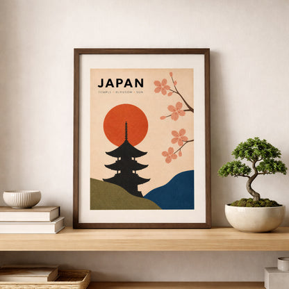 Vintage Japan wall art in a light wooden frame, styled on a simple shelf beside a small bonsai tree and neutral ceramic decor. The print shows a black Japanese pagoda, bold red sun, pink cherry blossom branches and curved green and blue hills on a warm cream background, adding calm travel style to the room.