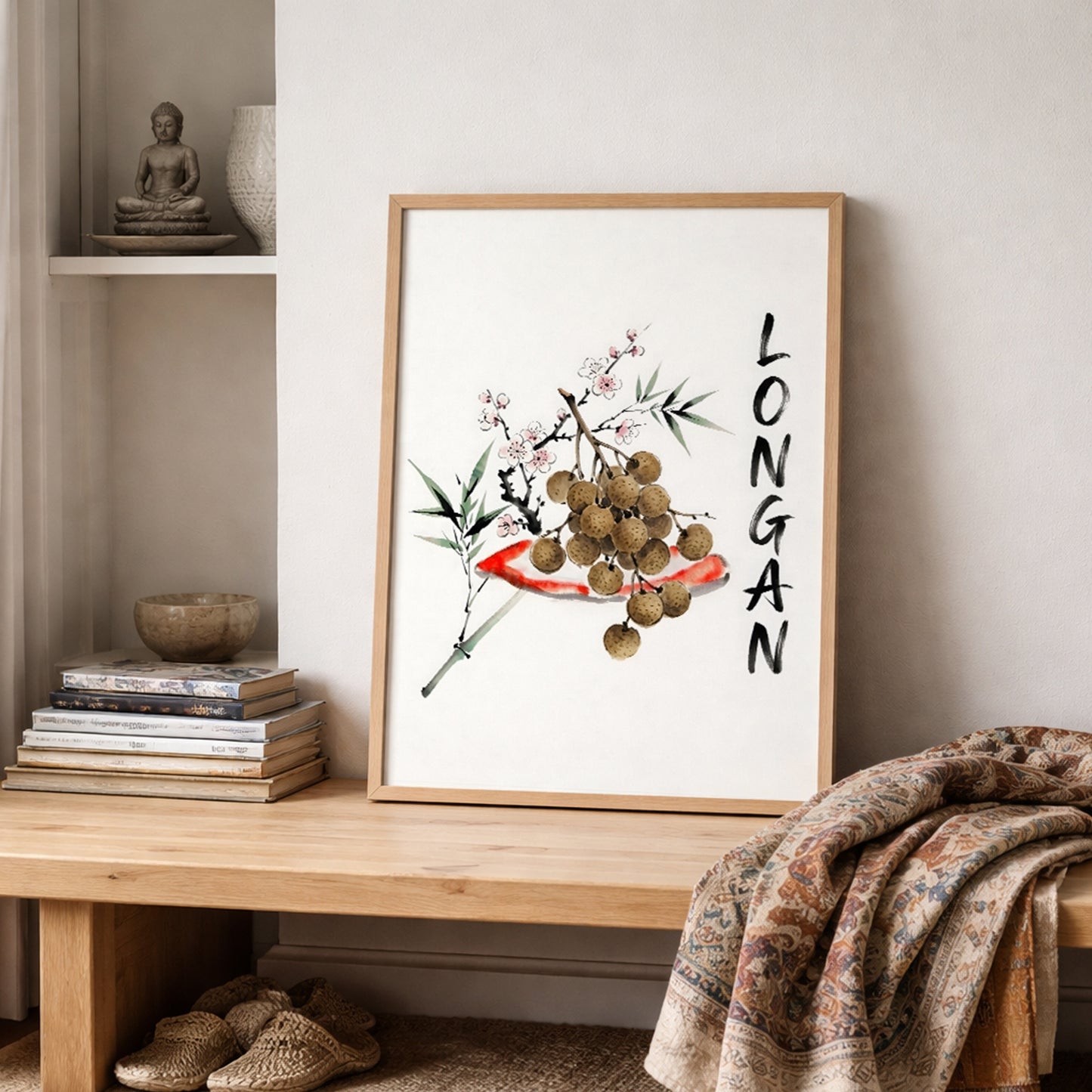 Thai longan watercolour print displayed on a shelf with layered neutral textiles and rustic decor. The artwork shows brown longan fruit on a branch, green leaves, blossom detail and vertical black lettering, making it a minimalist Southeast Asia inspired poster for kitchens, dining rooms and relaxed home styling.