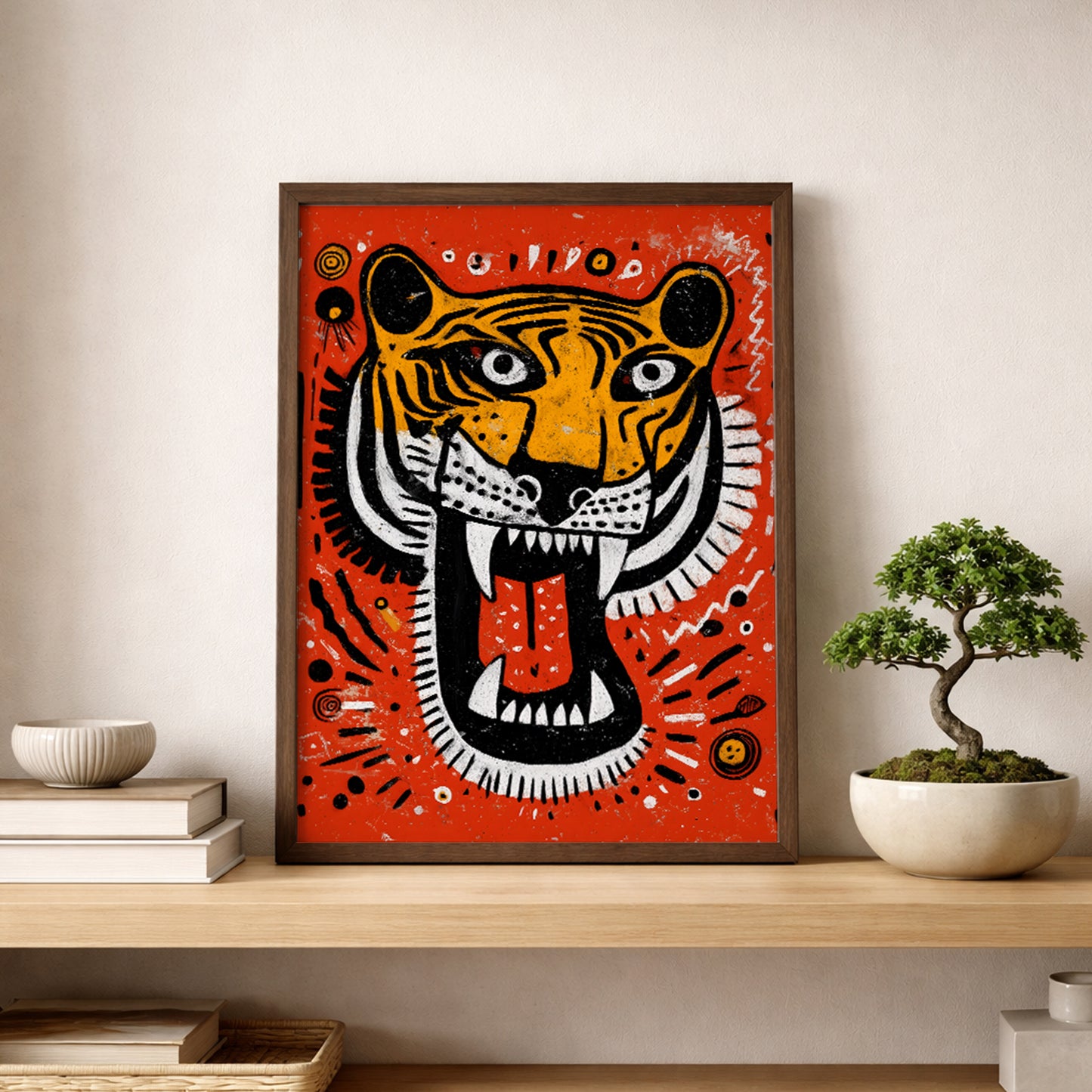 Roaring Malayan Tiger print leaning on a wooden shelf beside a bonsai plant. The bright orange background and sketch-style tiger face create contrast against neutral surroundings. Black and white stripes, red tongue and dotted tribal accents add strong graphic detail, making this Malaysian wildlife poster a bold focal point in creative workspaces.