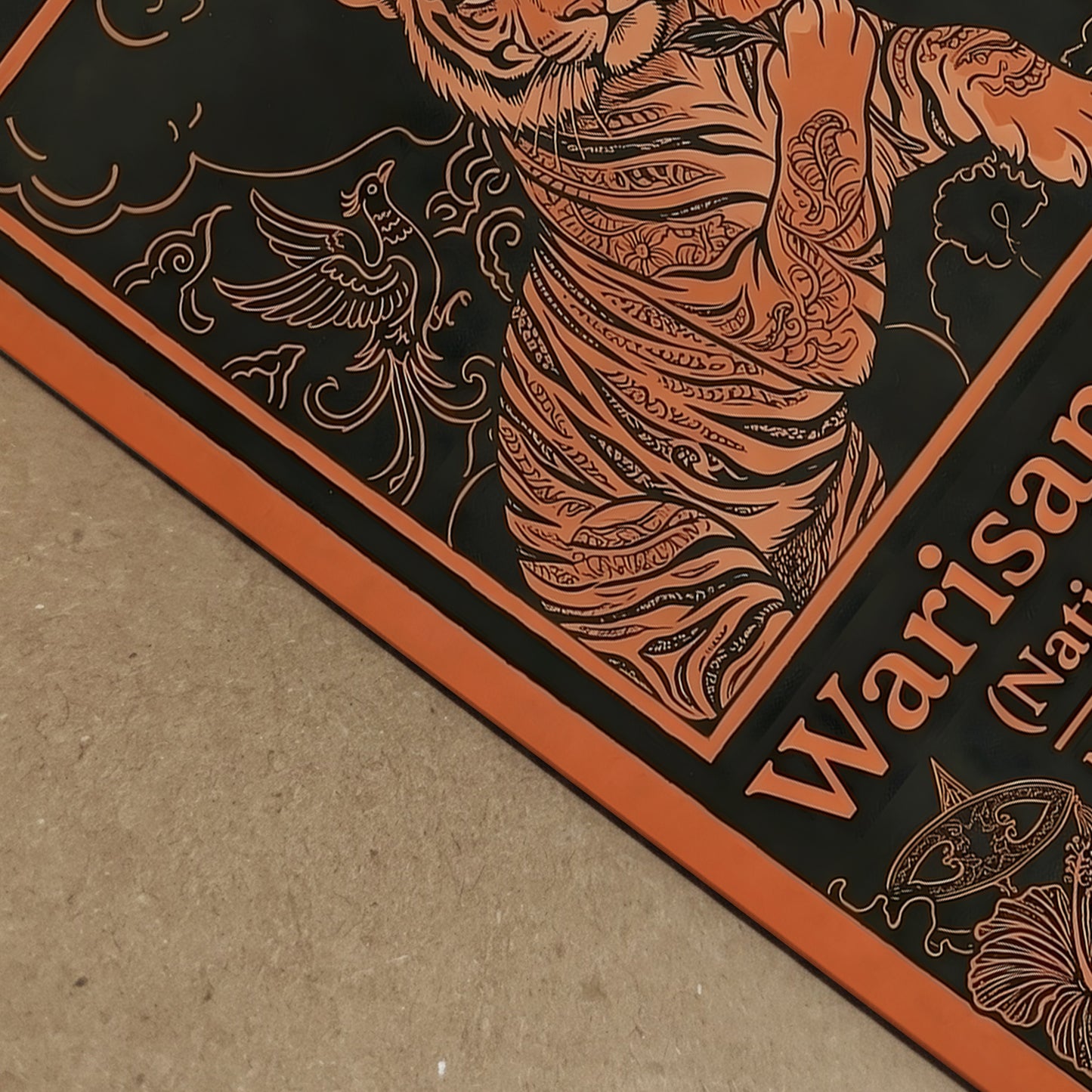 Close-up detail of the Warisan Bangsa National Heritage Malaysia poster showing the orange line illustration of a tiger, hibiscus flower and decorative floral patterns printed on textured paper. The vintage inspired Malaysian culture artwork uses strong graphic lines and ornamental borders against a dark background, highlighting traditional decorative illustration and national symbolism.