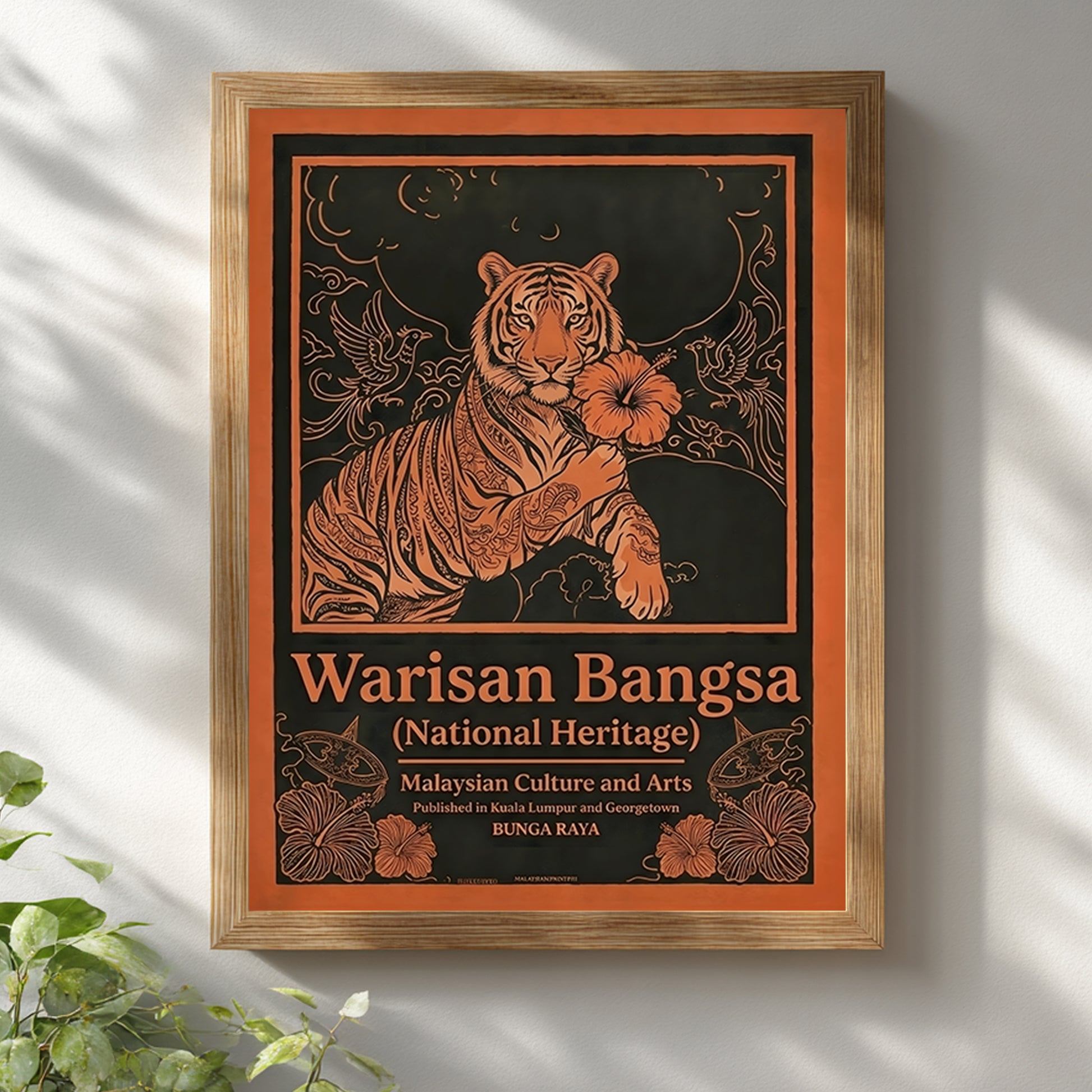 Malaysia tiger wall art Warisan Bangsa National Heritage displayed in a wooden frame on a neutral white wall. The poster features a stylised tiger holding a hibiscus flower with surrounding birds and decorative floral lines illustrated in bold orange against a dark background. Malaysian heritage poster design inspired by traditional culture and vintage decorative illustration.
