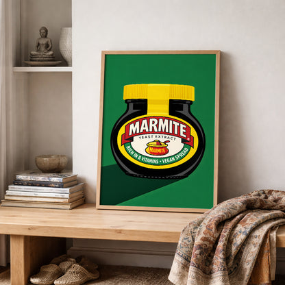 Marmite Jar Print propped on a shelf in a styled interior with books, ceramics and a folded textured throw nearby. The bold green background and classic black Marmite jar create a clean pop art look with a playful British food reference. The image shows how the artwork fits easily into modern interiors as quirky British wall art, kitchen decor or casual framed shelf styling.