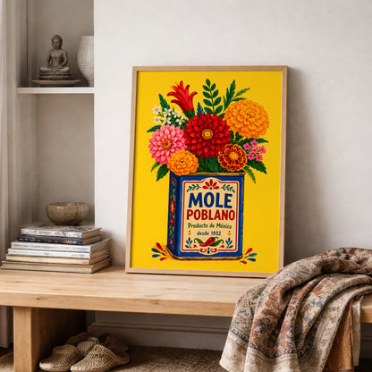 Mexican mole poblano poster leaning on a wooden shelf in a softly styled neutral interior, placed beside stacked books, pottery and a textured woven throw. The yellow background, blue vintage tin and colourful flowers bring bold Mexican food culture and folk-inspired colour into a calm kitchen, dining or living space.