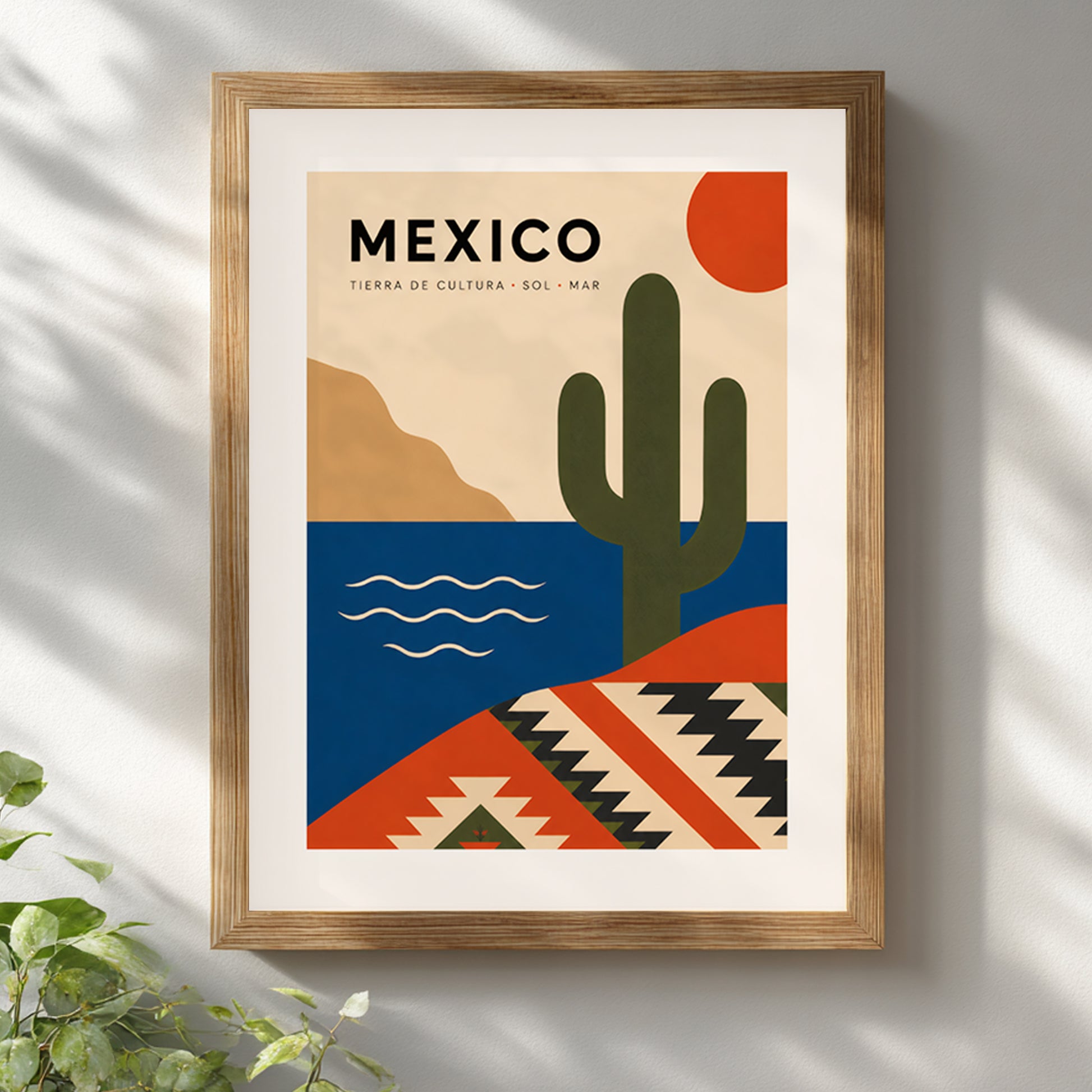 Natural wood framed Mexico travel poster hanging on a clean white wall with soft sunlight and leafy shadows across the room. A green plant adds a relaxed finishing touch, while the cactus, red sun, blue sea and geometric Mexican pattern bring warm colour to a bright modern living space.