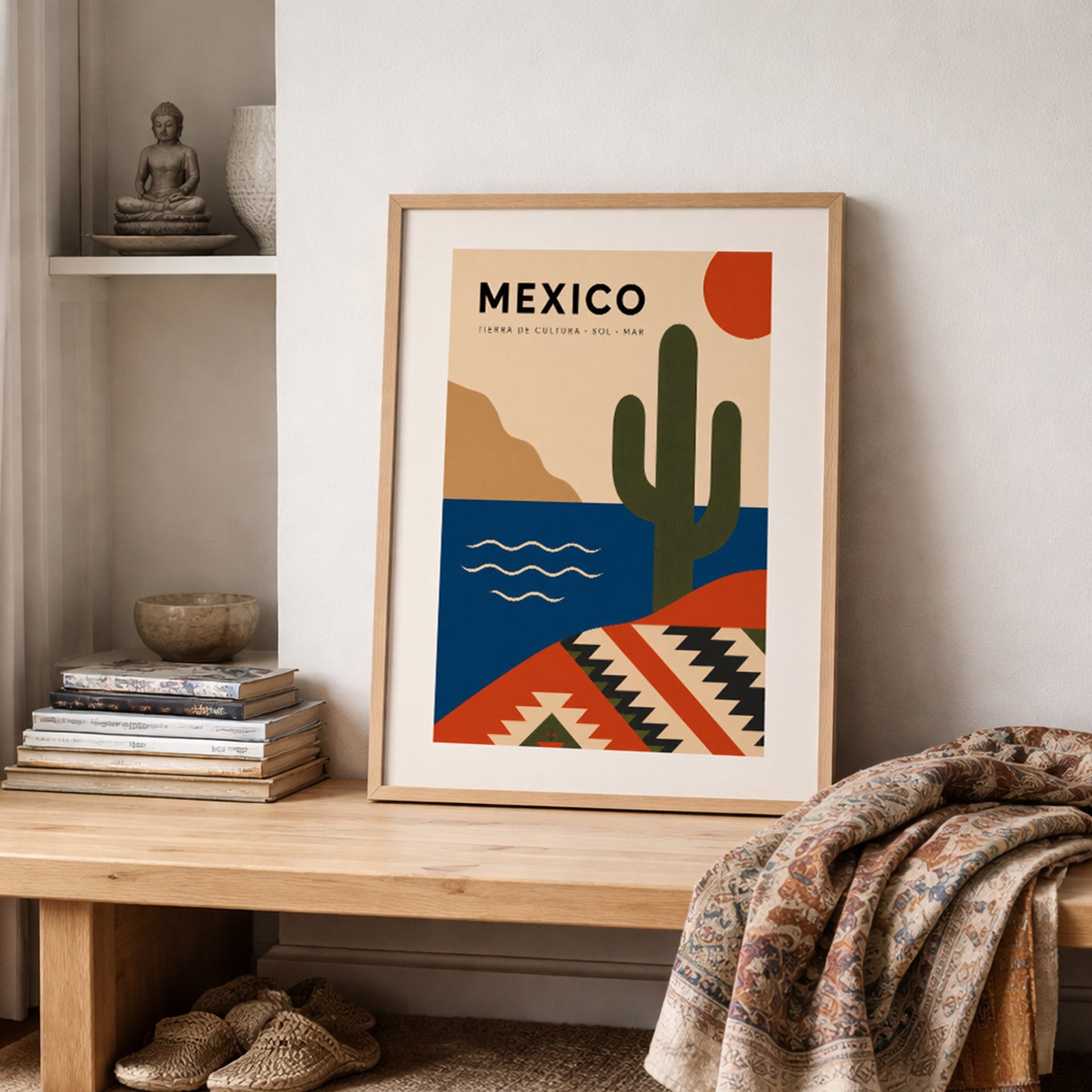 Mexico travel poster in a natural wood frame styled on a shelf with books, neutral decor and a soft patterned throw. The colourful cactus, sun, sea and geometric Mexican design adds a bold but balanced focal point, ideal for cosy living rooms, bedrooms and travel-themed home interiors.