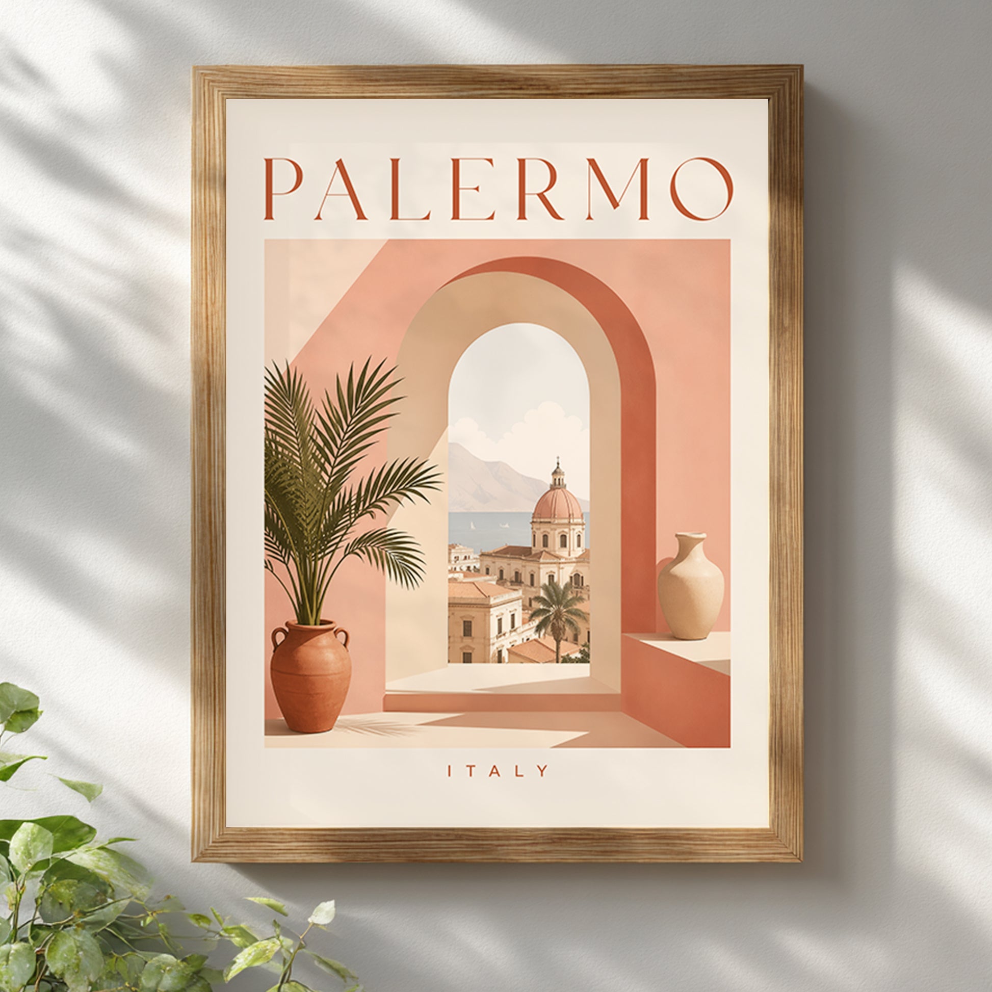 Palermo travel poster displayed in a light wooden frame on a bright white wall with soft leafy shadows. The artwork uses peach, cream and terracotta tones to show an arched Sicilian city view, potted palm and PALERMO title. A warm, sunlit mock-up for Italian wall art, Mediterranean interiors and modern travel decor.
