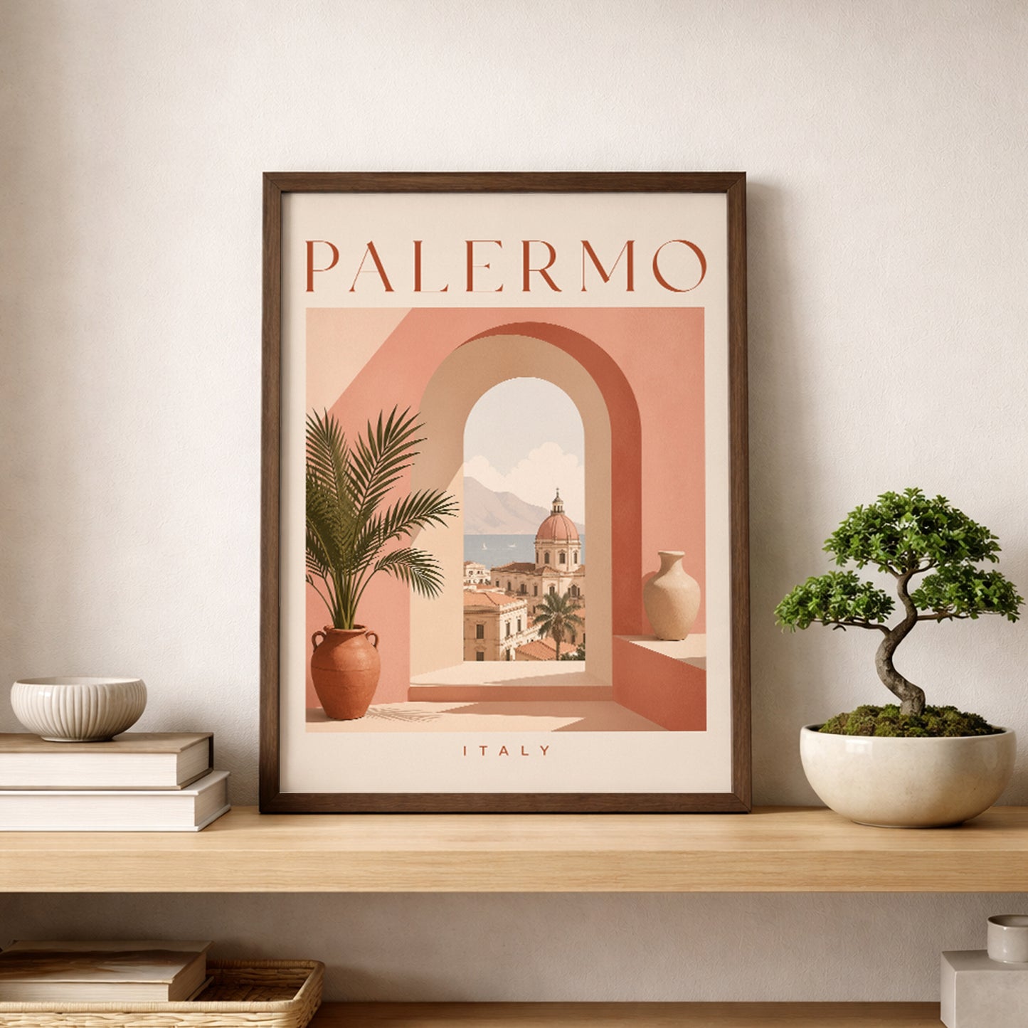 Palermo travel print in a slim dark frame, styled on a pale wooden shelf beside a small bonsai tree and neutral ceramic bowl. The poster combines peach, terracotta and cream tones with an arched Sicilian cityscape and potted palm. A clean modern display for Italian wall art, Mediterranean decor and travel poster interiors.