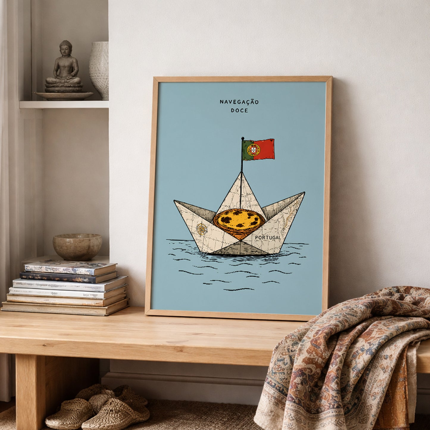 Framed Portugal food print featuring a pastel de nata sailing boat, styled on a wooden shelf beside stacked books and a draped woven textile.