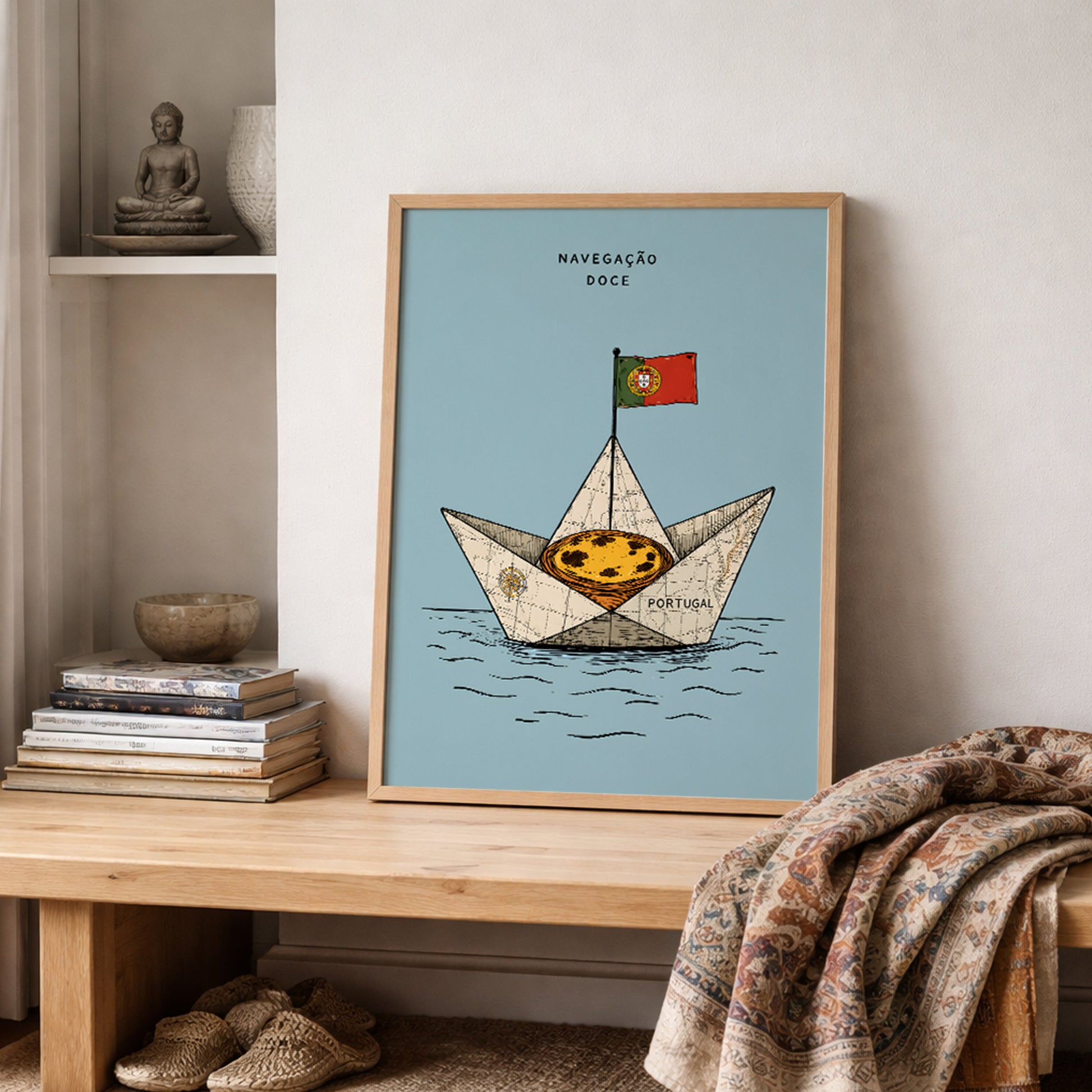 Framed Portugal food print featuring a pastel de nata sailing boat, styled on a wooden shelf beside stacked books and a draped woven textile.