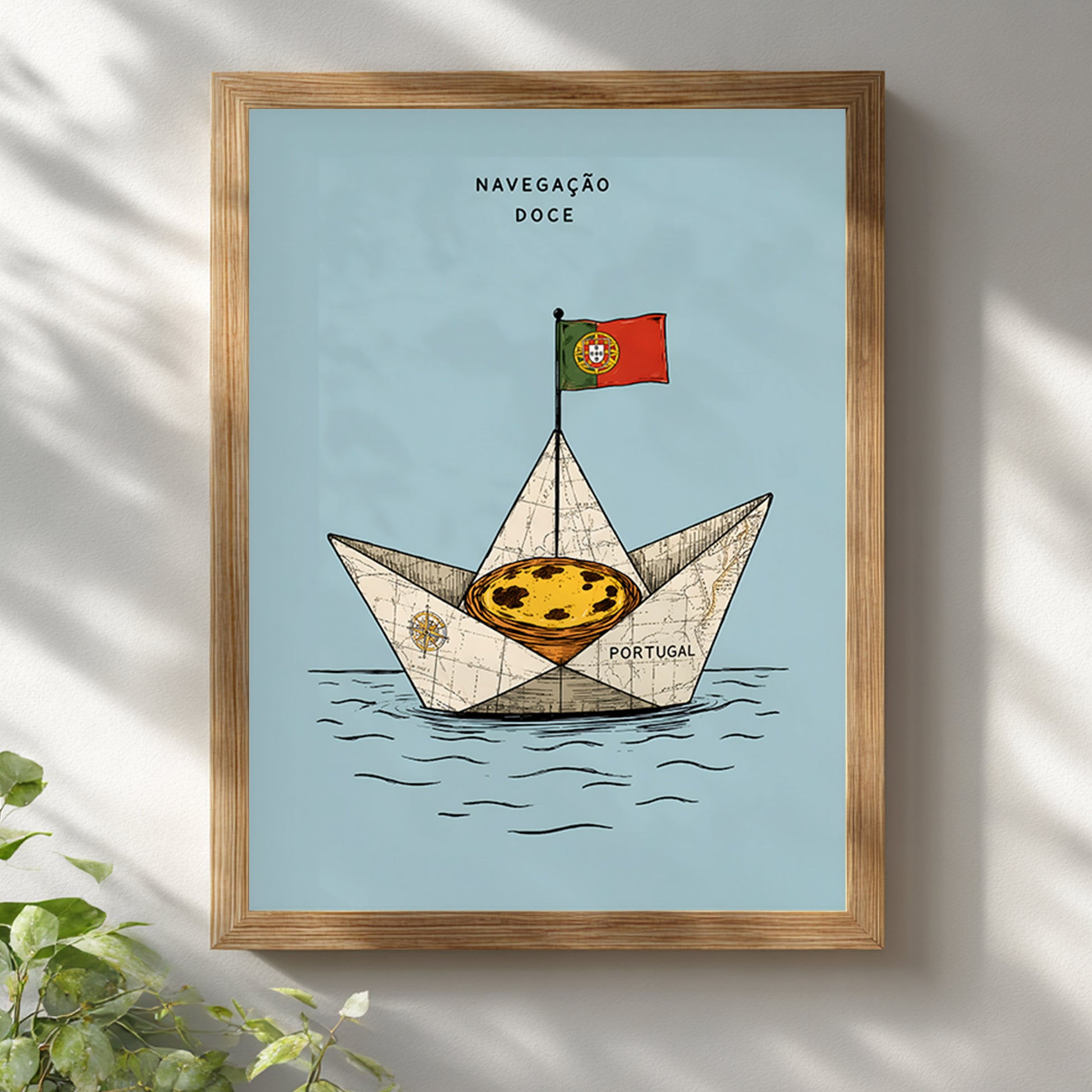 Pastel de nata sailing boat print displayed in a natural wooden frame on a white wall with soft sunlight and leafy shadows.