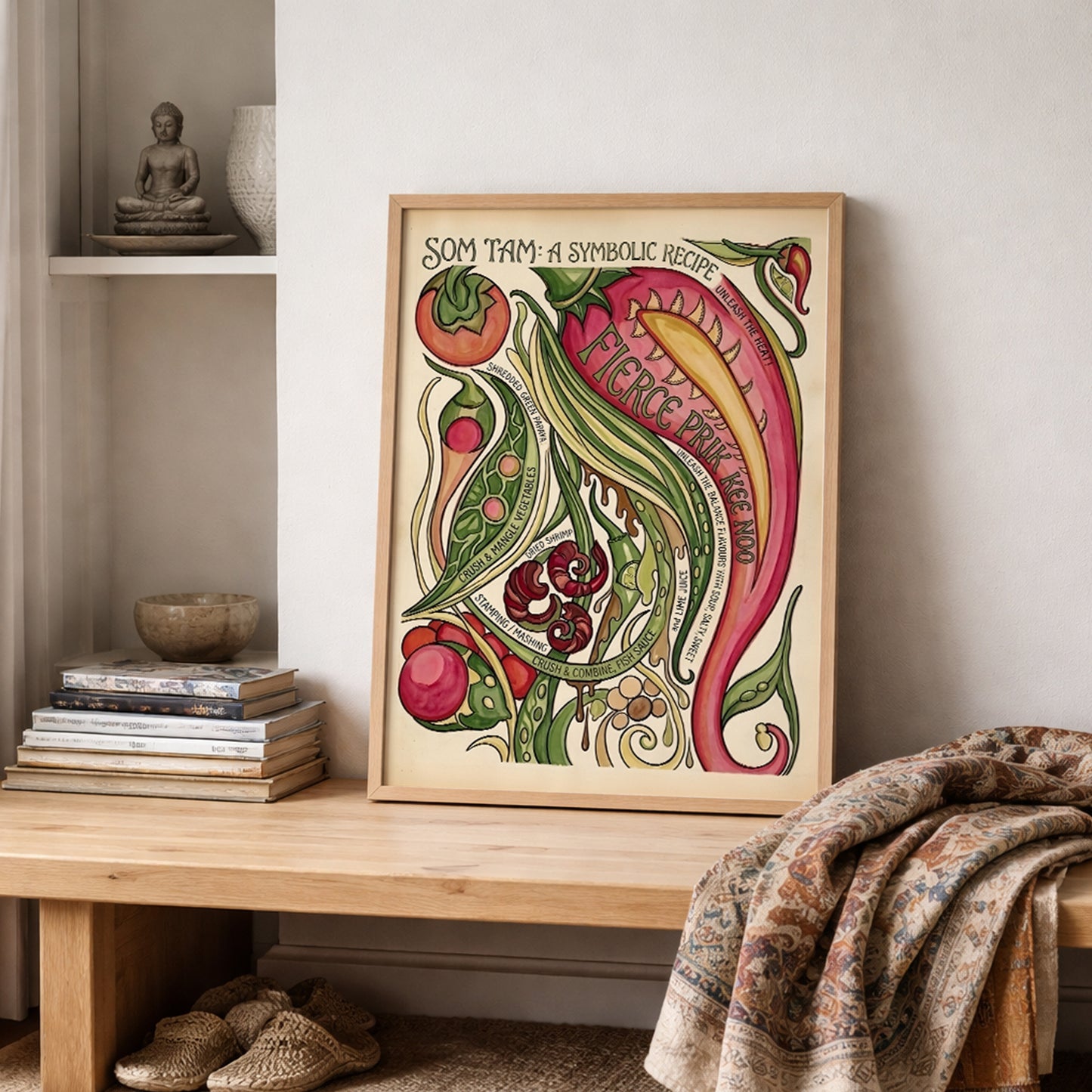 Framed Som Tam Recipe Print leaning on a shelf in a lived-in interior with folded textiles and neutral decor nearby. The mockup shows the Thai cuisine wall art in a relaxed home setting, with the colourful ingredients and curved recipe text adding movement and detail. The hand-painted style makes it suited to kitchen decor, food corners and dining spaces that need a bold but easy focal point.