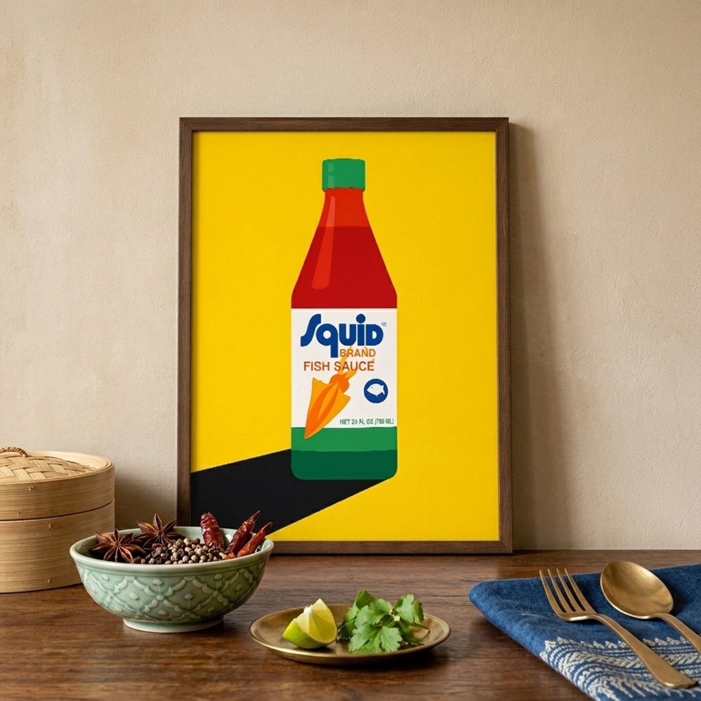 Squid Fish Sauce pop art poster styled in a warm kitchen or dining setting above a table with food, bowls and tableware. The framed print features a Thai fish sauce bottle on a vivid yellow background, adding a bold colour pop to the interior. This lifestyle mockup presents the artwork as playful kitchen wall art, food-inspired home decor and modern pop art print suitable for dining rooms and gallery walls.