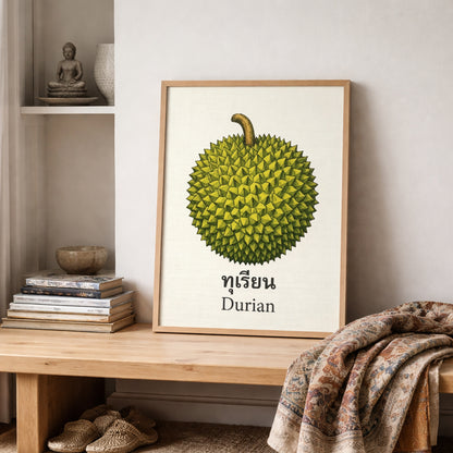 Framed durian wall art placed on a wooden shelf in a relaxed room with books, textiles and patterned rugs. The print shows a detailed green durian fruit above Thai text and the English word “Durian” on a cream background. The setting gives the artwork a collected look and shows how it fits into pantry decor, dining spaces, cultural interiors and tropical fruit gallery walls.