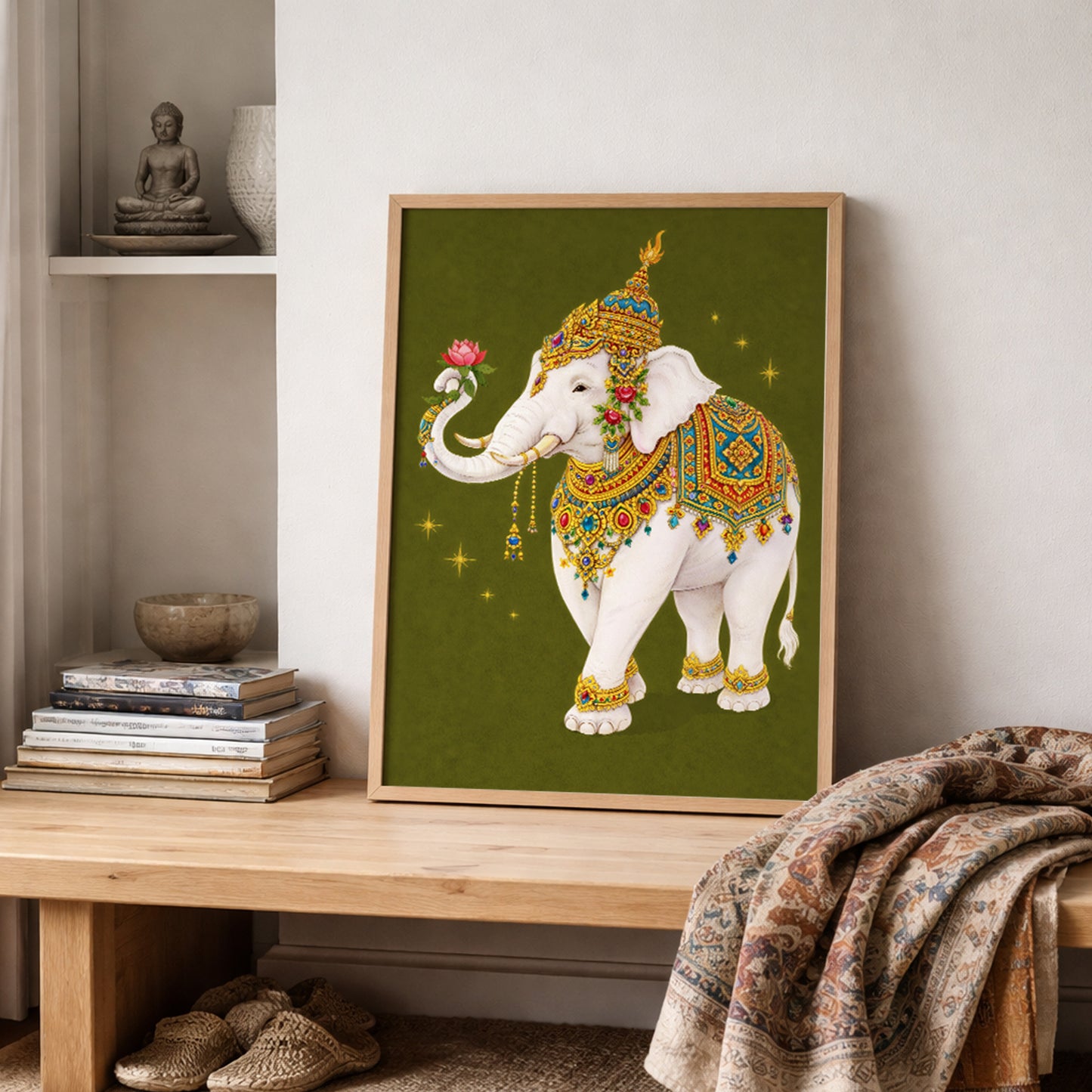 Thai royal white elephant wall art leaning on a wooden shelf with folded textured fabrics and neutral décor. The sacred elephant features ornate gold detailing, colourful Thai-inspired patterns and a lotus flower in its trunk. The olive green background and soft natural light highlight the traditional royal symbolism within a contemporary cultural interior setting.
