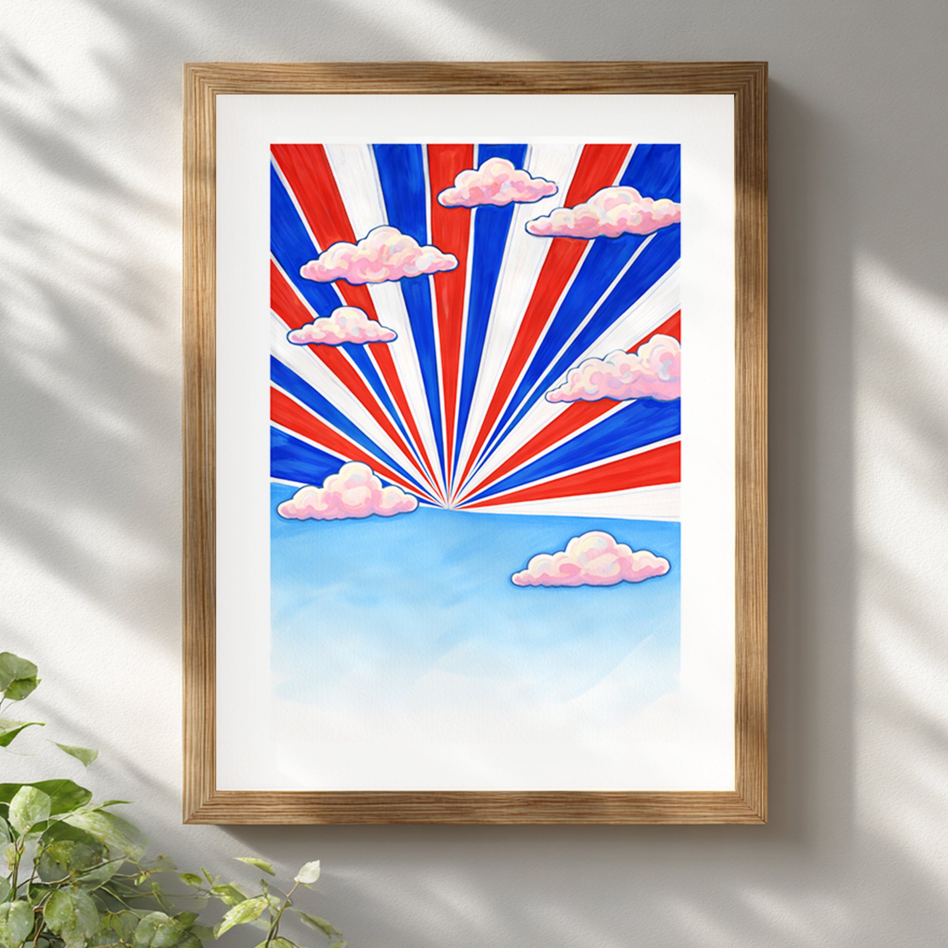 Thailand travel poster in a natural wooden frame on a white wall. Red, white and blue sunburst rays inspired by the Thai flag rise over a blue horizon with pink clouds. Modern Southeast Asia wall art print styled for contemporary living room or office decor.