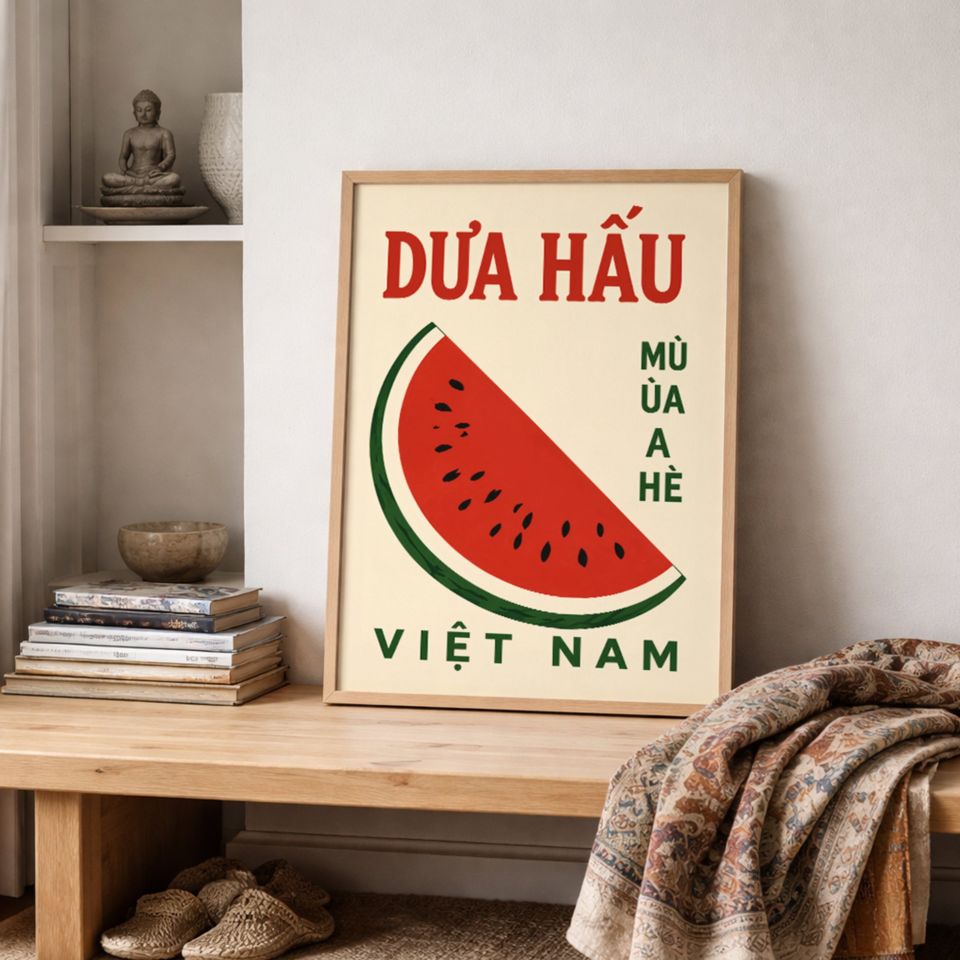 Vietnam watermelon wall art styled on a shelf with folded textiles and soft neutral decor. The poster shows a red watermelon slice, black seeds, green rind and bold Vietnamese lettering on a cream background, creating a simple food print for kitchens, dining spaces or relaxed home styling.