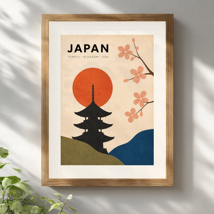 Vintage Japan travel poster in a natural wooden frame on a white wall, lit by soft daylight and gentle leaf shadows. The black temple silhouette, red rising sun, pink cherry blossoms and curved green and blue hills create warm retro Japanese wall art suited to a living room, bedroom, hallway or home office.