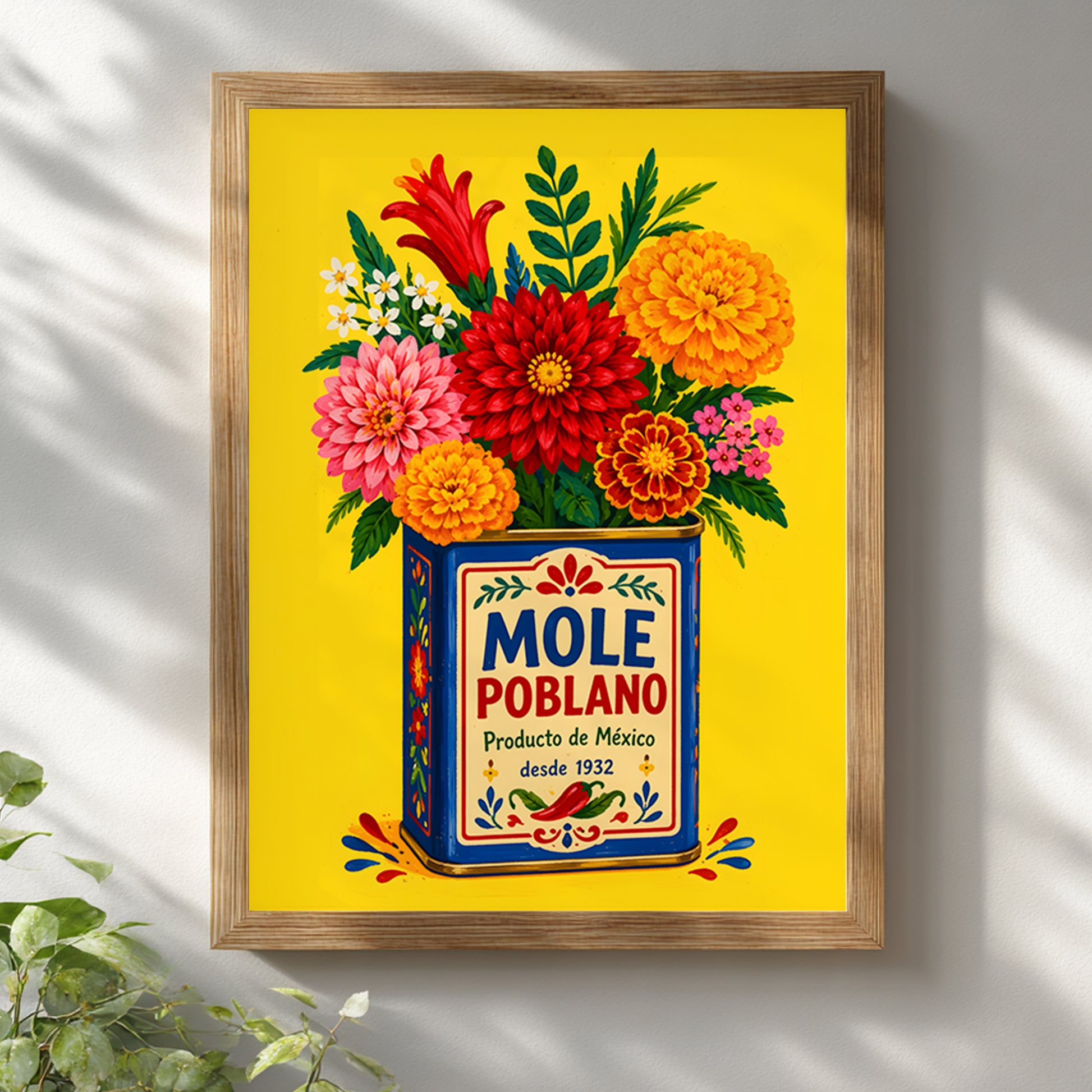 Mexican mole poblano print displayed in a light wooden frame on a white wall, with soft window shadows falling across the artwork. The bright yellow background, blue vintage tin and red, pink and orange flowers create colourful Mexican kitchen wall art that works well in bright, simple interiors.