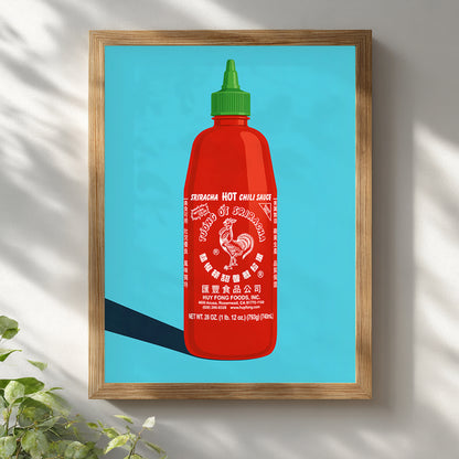Wooden framed sriracha poster on a white wall with soft plant shadows, featuring a red hot sauce bottle, green cap, white rooster label and bright blue background. A colourful kitchen wall art print for dining rooms, cafes, food shops, restaurant decor and modern foodie gallery walls.