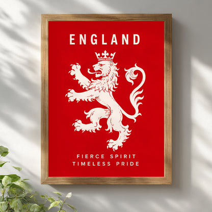 Framed England wall art featuring a white lion rampant on a bright red background, with the word ENGLAND at the top and the phrase FIERCE SPIRIT TIMELESS PRIDE at the bottom. The print is shown in a light wood frame against a white wall with soft leaf shadows and a small plant at the lower left.