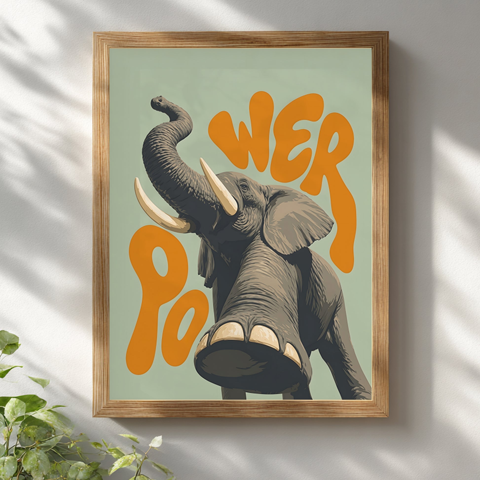 Wooden framed elephant wall art hanging on a white wall, featuring a grey elephant with raised trunk, large tusks, detailed texture and orange retro lettering on a soft green background. A bright safari animal poster for natural home decor, living room wall art, kids’ room decor or office wall styling.