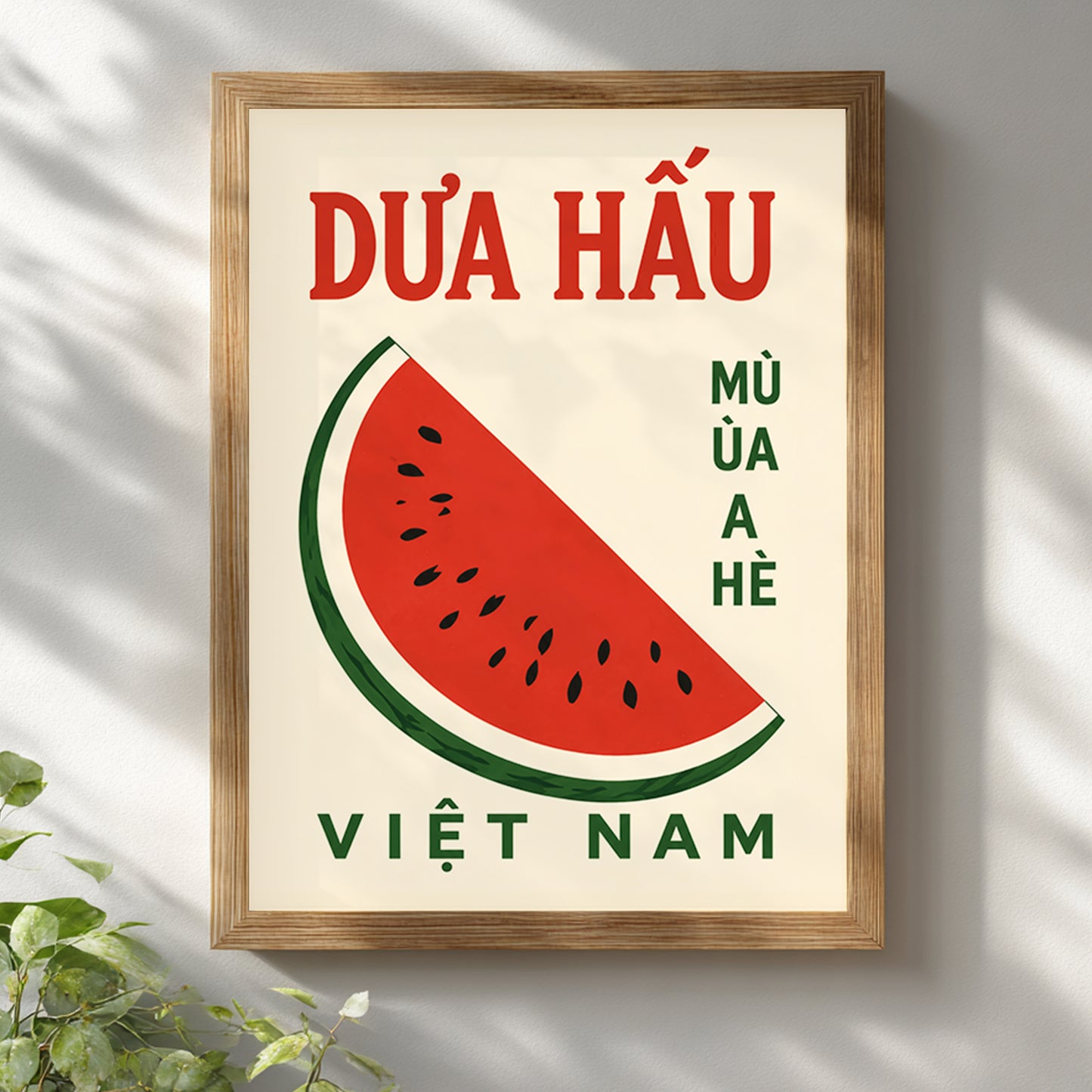 Wooden framed Vietnam watermelon poster hanging on a bright white wall near soft natural light. The design includes a red watermelon slice, green rind, black seeds and Vietnamese text on a cream background, styled as simple fruit wall art for kitchens, cafes, dining rooms or travel decor.